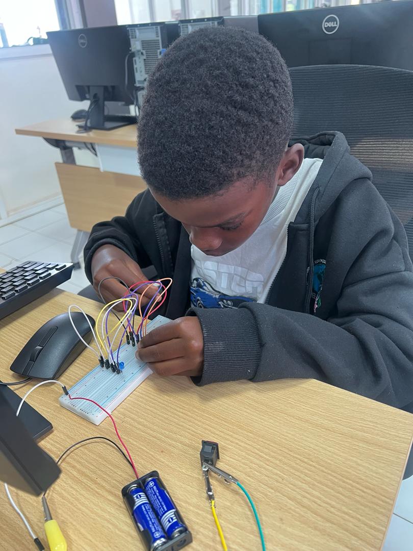 A boy assembling a circuit on a breadboard